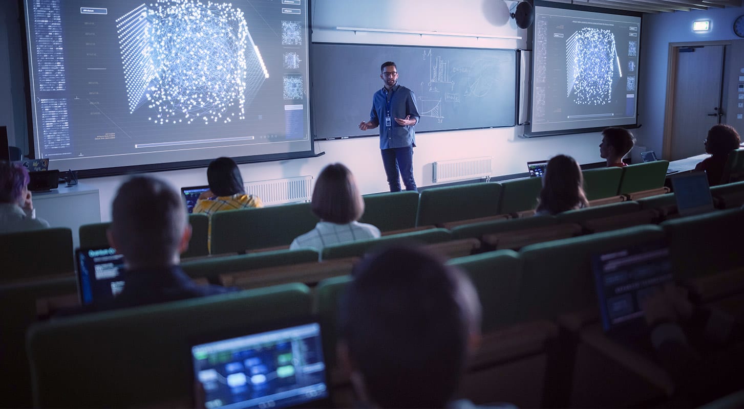 A professor delivering a lecture to students in a classroom setting, engaging with the audience.